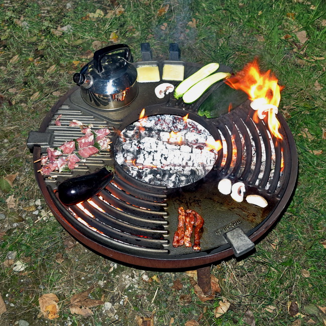 Die Feuerküche im Einsatz mit Grillgut, Wassertopf und Raclette